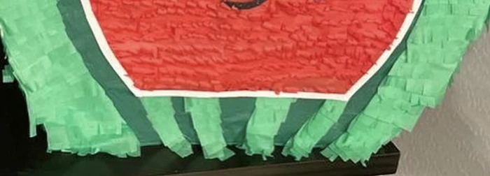 Close-up of layered green tissue-paper fringe on the base of a watermelon pi&ntilde;ata