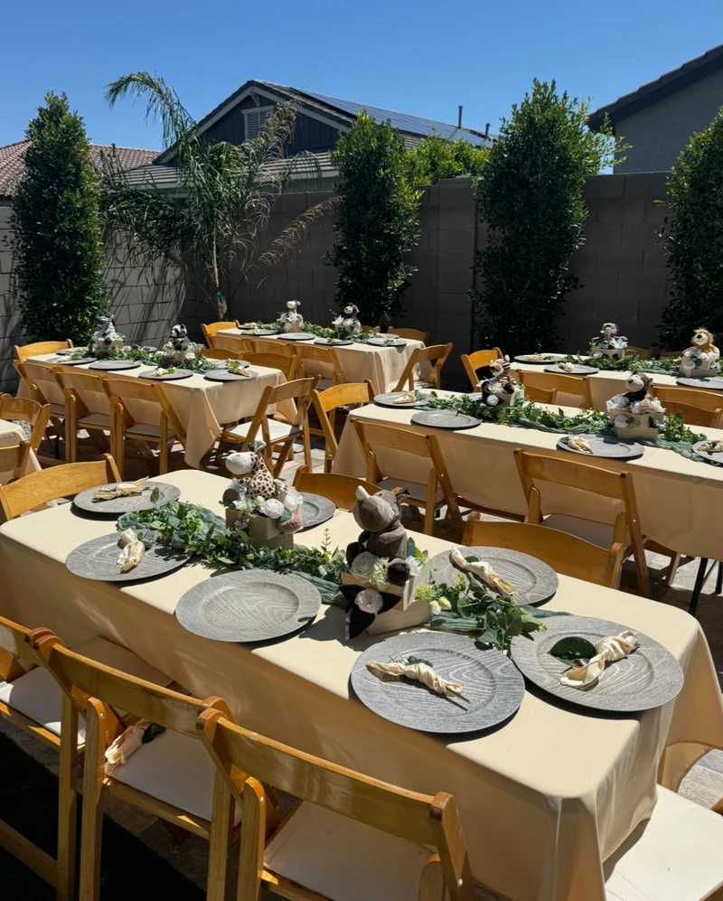Long outdoor banquet tables set with greenery runners, stone linen and matching centrepieces