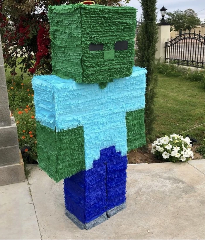 A green blocky character pi&ntilde;ata standing on a garden path outside a Phoenix home