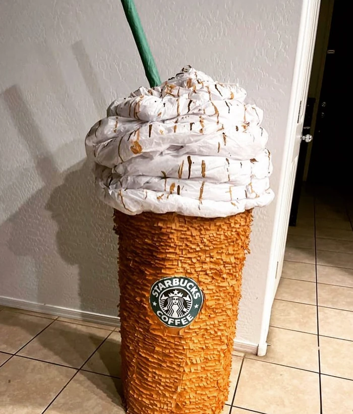 A custom pi&ntilde;ata shaped like a tall iced-coffee cup with sculpted whipped cream and a green straw