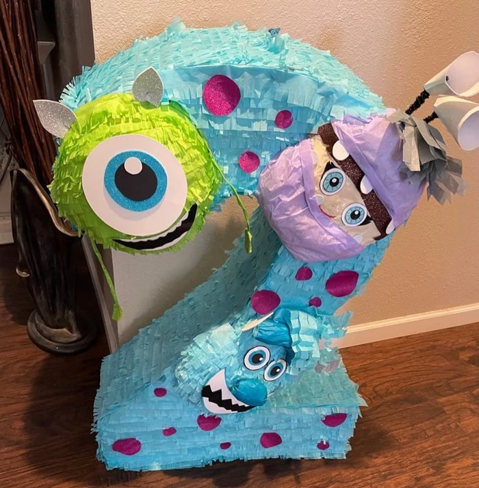 A number-two pi&ntilde;ata in blue with two cartoon monster characters attached