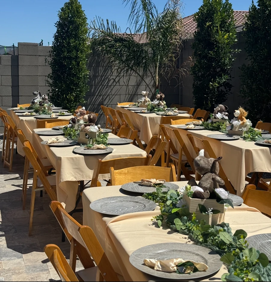 A long run of outdoor banquet tables with greenery runners and matching centrepieces